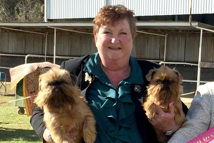 Kerry Bell holds her two dogs under her arms at an outdoor dog show.