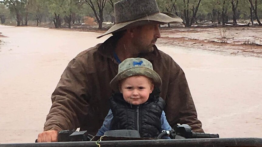 A little boy and his dad on a property in the rain