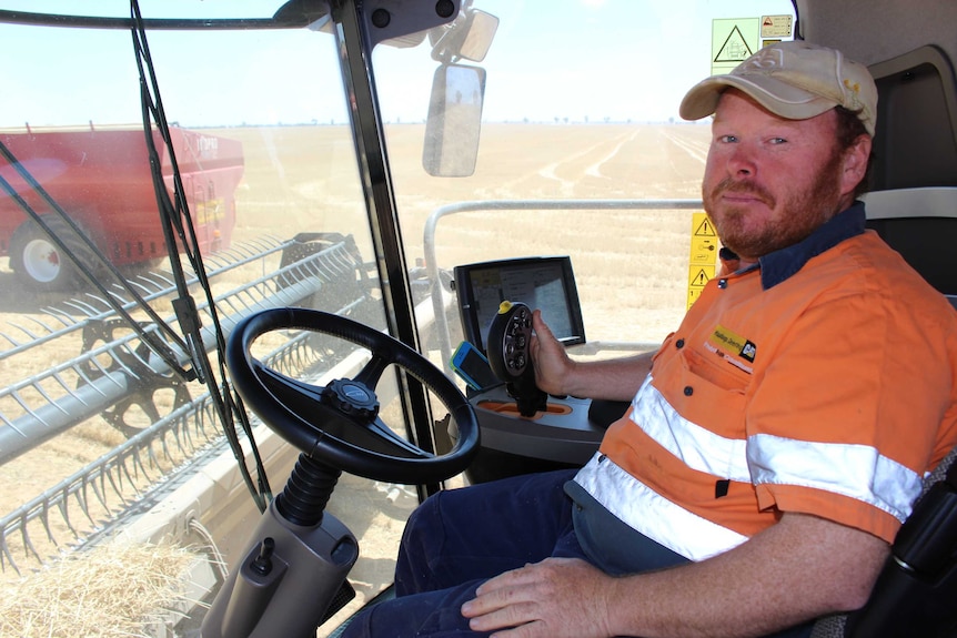 Man sitting he drivers seat of a header looking at the camera.