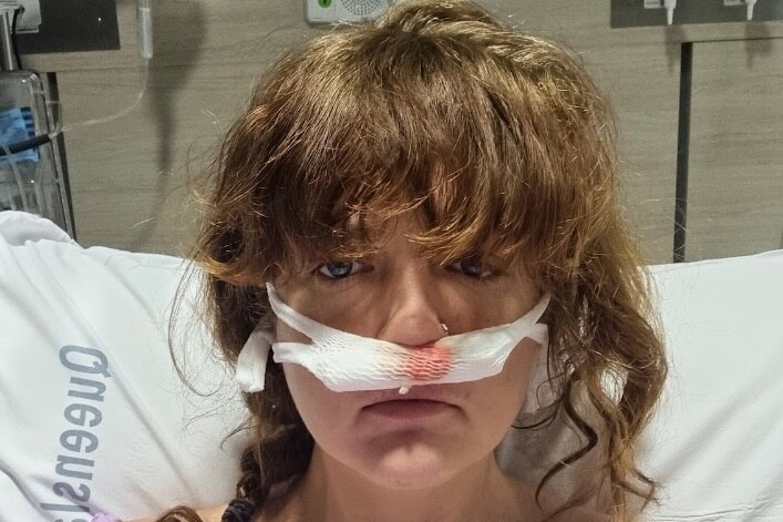 Woman in hospital bed with bandage across face
