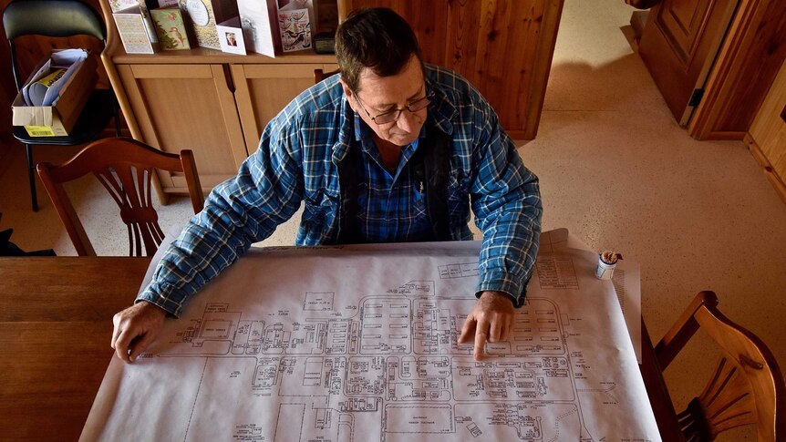An overhead shot of an older man with a blue shirt looking at a map