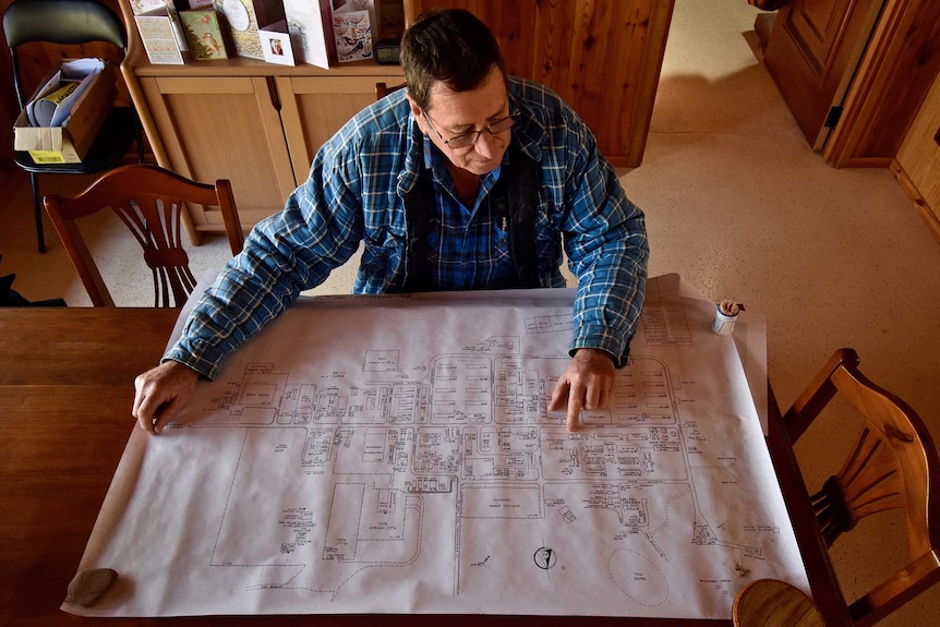 An overhead shot of an older man with a blue shirt looking at a map