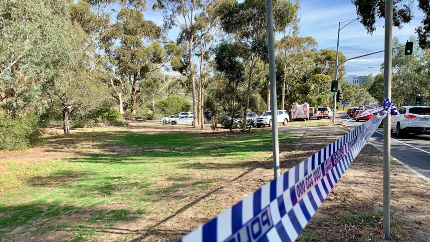 Police tape seals an area of parkland facing busy Eilliott Avenue in Parkville.