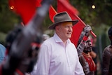 Anthony Albanese, wearing a hat, walks among indigenous performers.