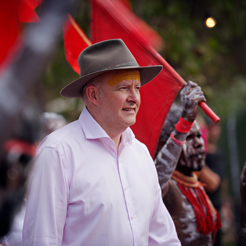 Anthony Albanese, wearing a hat, walks among indigenous performers.