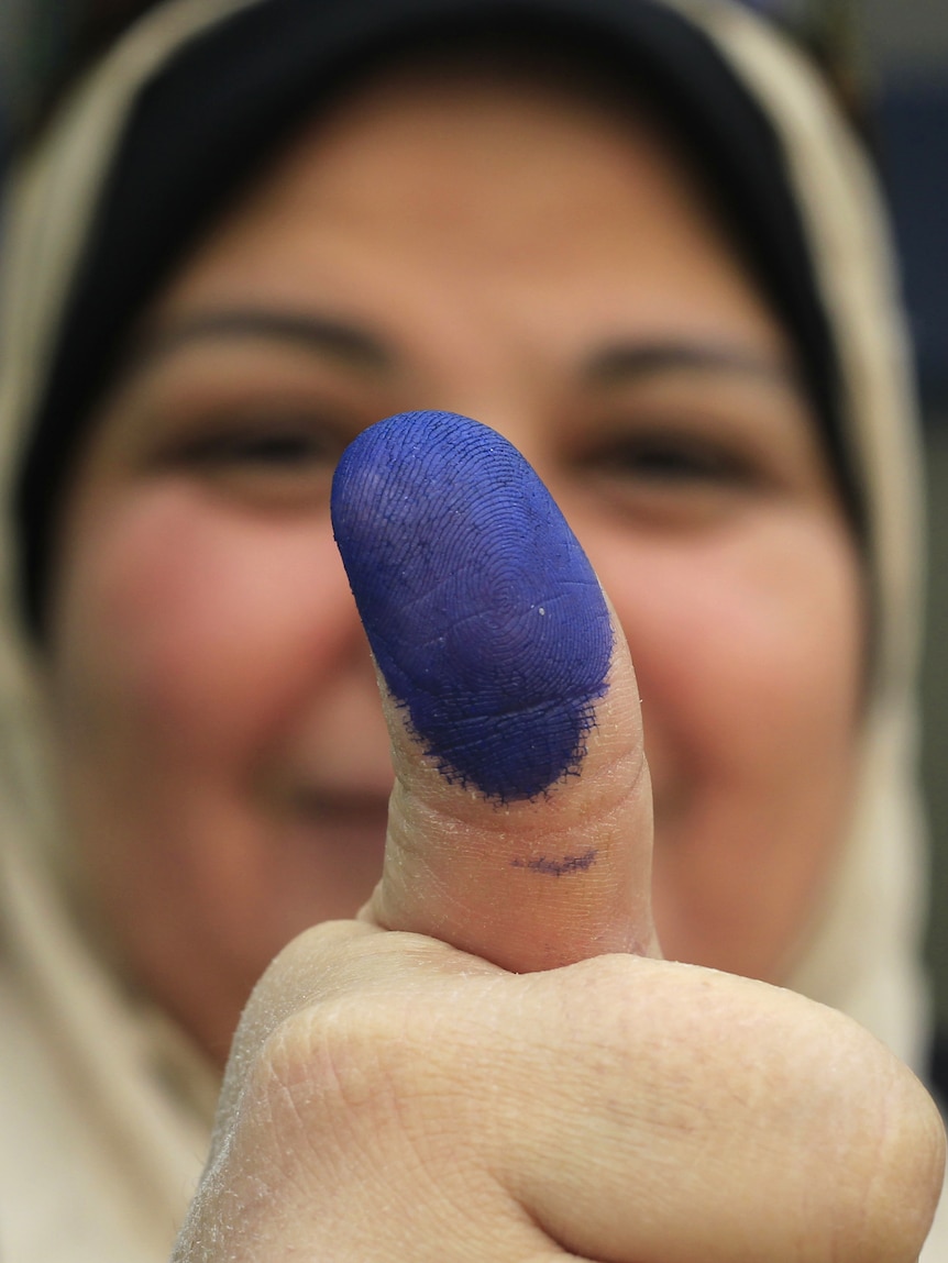 An Egyptian woman shows her ink-stained thumb after voting at a polling station in the Manial neighbourhood of Cairo.