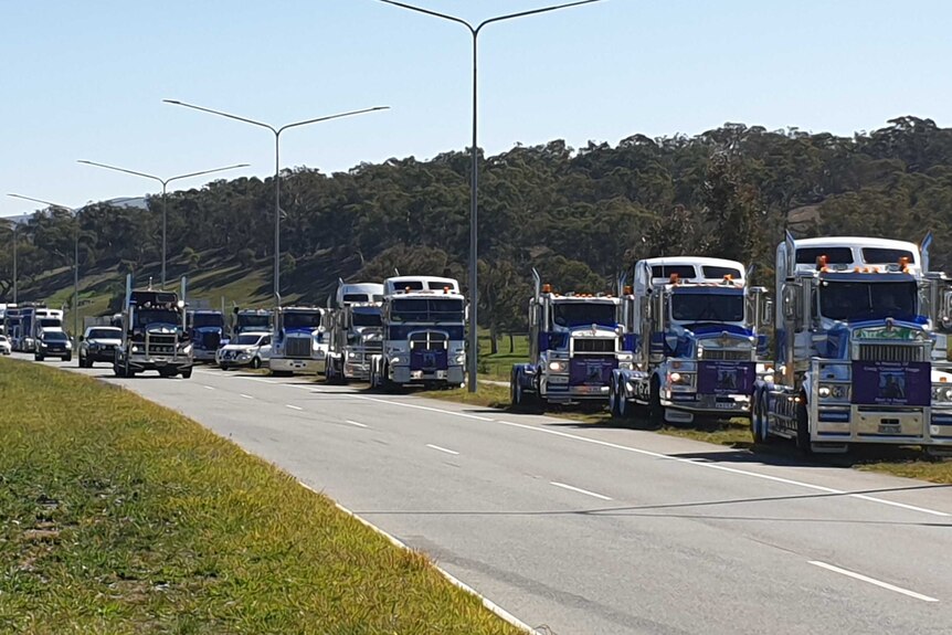 A convoy of trucks on the side of a road.