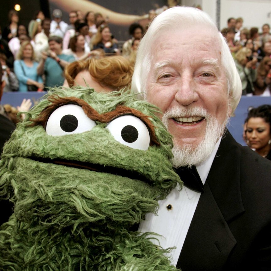 Caroll Spinney wears a tux and poses with Oscar the Grouch