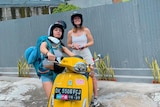 Two women wearing helmets on a rented scooter in Bali.