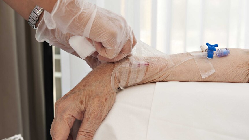 elderly hand with a drip attached