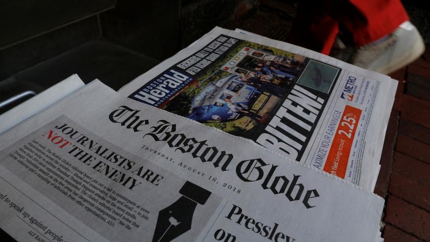 Two broadsheets newspapers can be seen on a table.