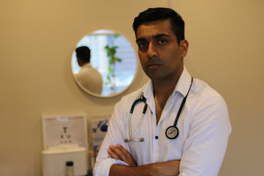 Dr Vyom Sharma stands in his rooms with his arms crossed.