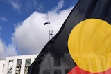 An Aboriginal flag in the foreground, Parliament House in the background