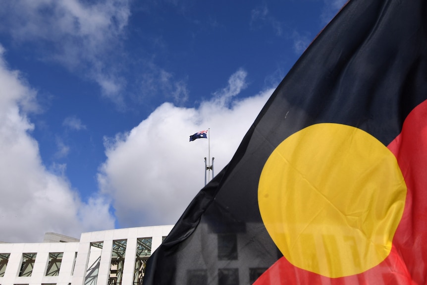 An Aboriginal flag in the foreground, Parliament House in the background