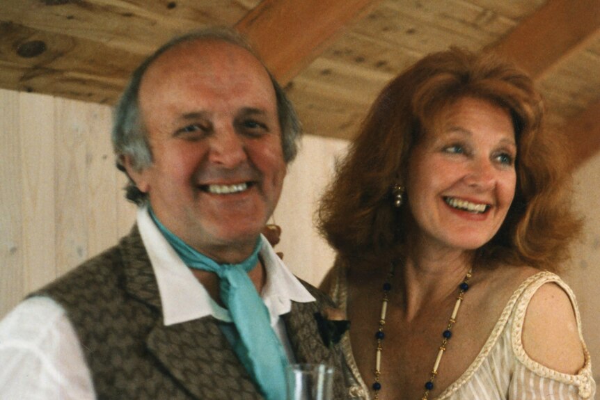 A man and a woman on their wedding day, smiling holding a drink