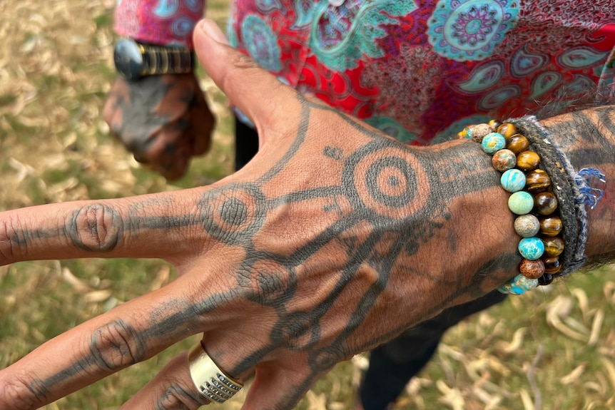 A man shows the Indigenous-designed tattoos on his hand. 