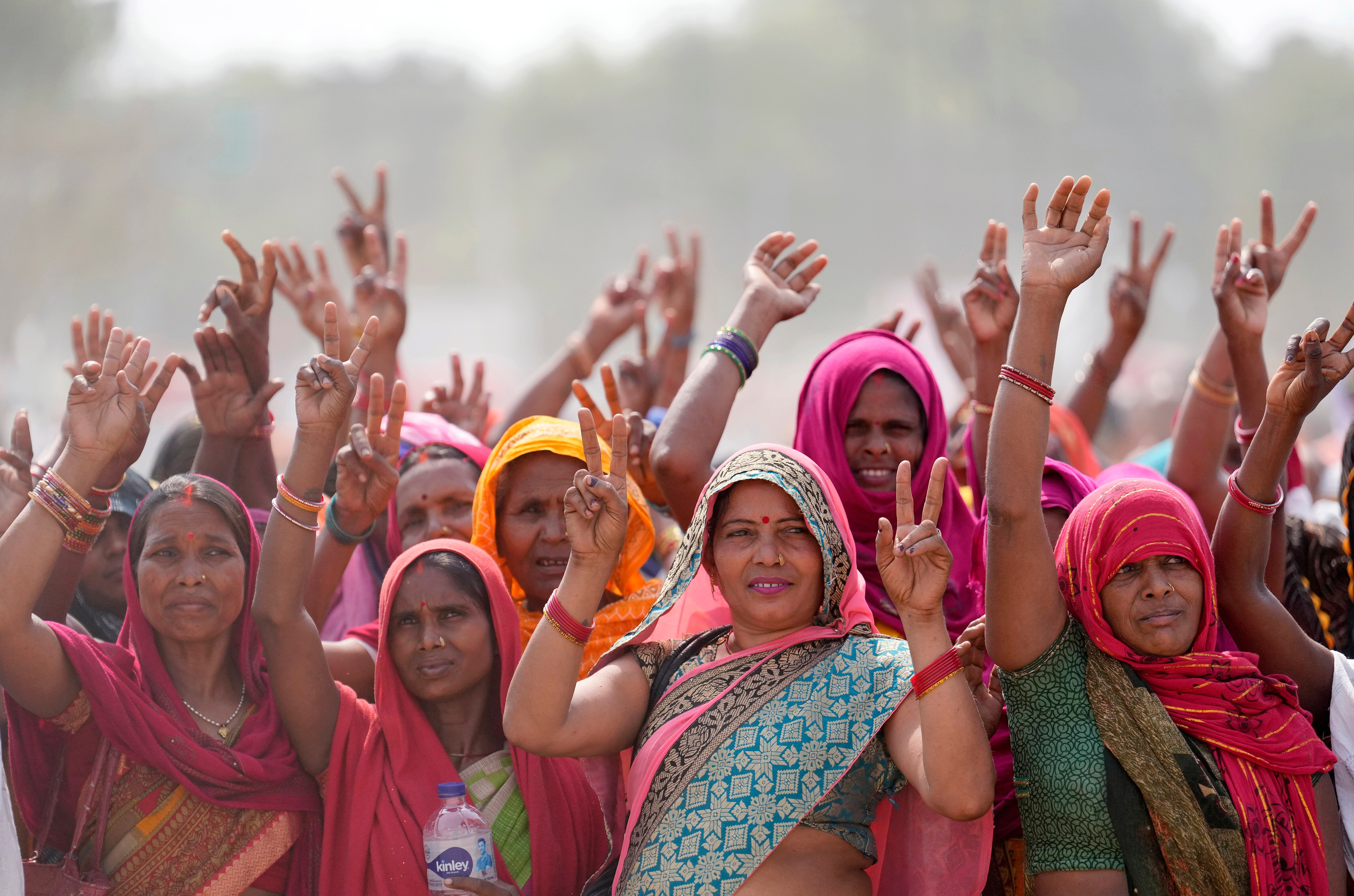 Women in saris waving and throwing peace signs 