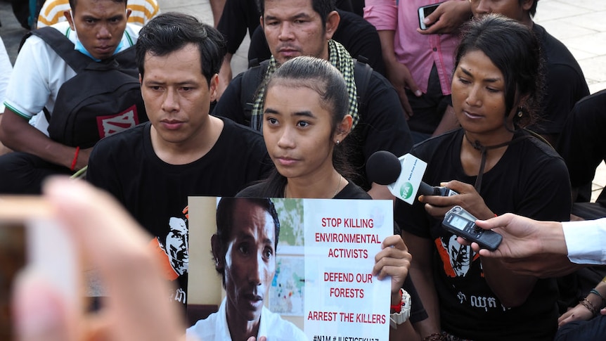 A Cambodian woman holds a photo of her murdered father.