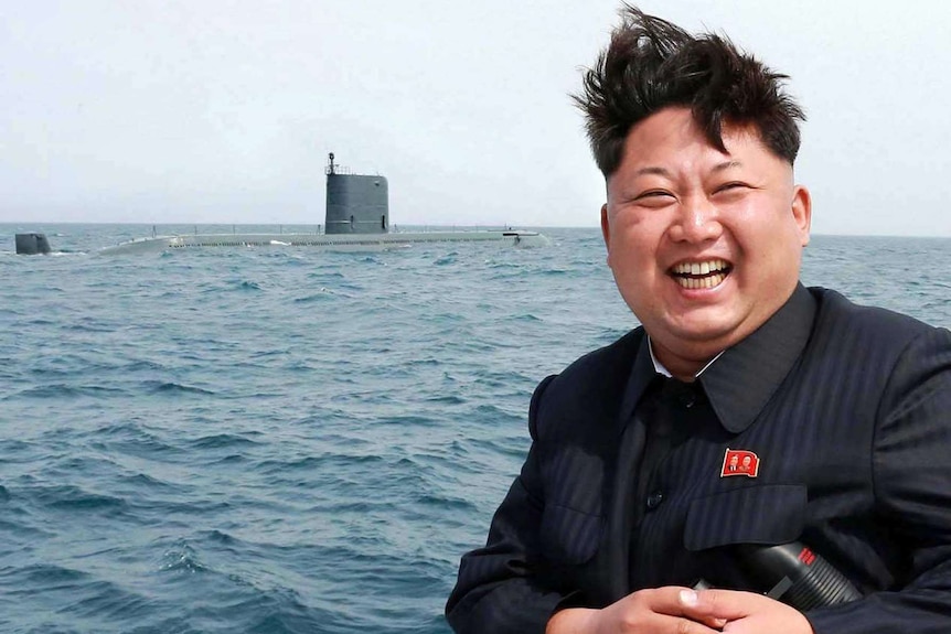 North Korean leader Kim Jong-Un laughs while sitting at an undisclosed location at sea.