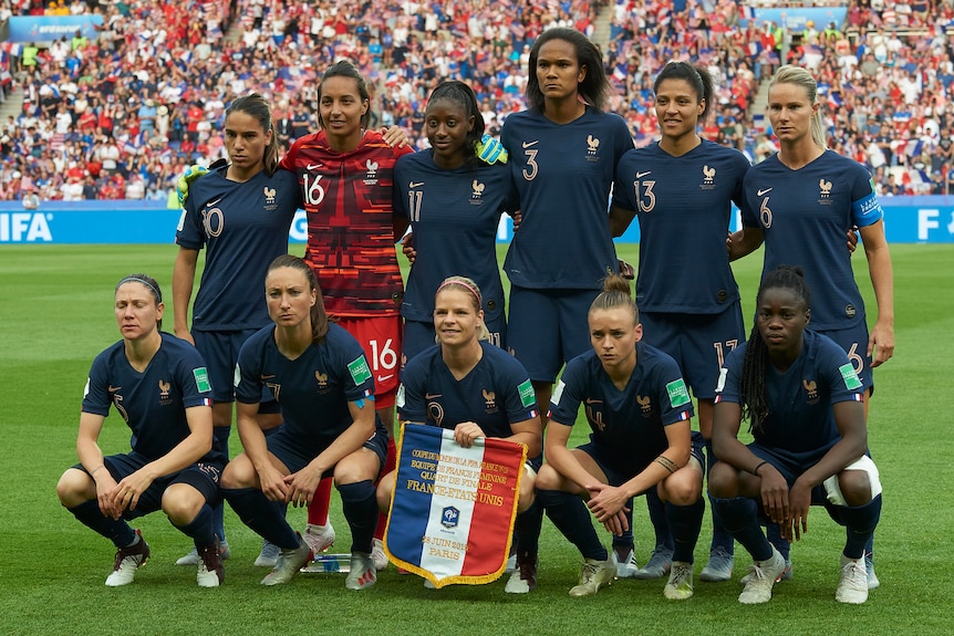 A women's soccer team wearing blue and red poses for a photo