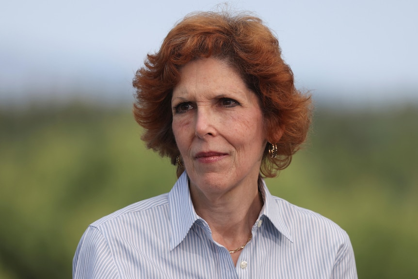 A woman with cropped red hair looks off to the side 