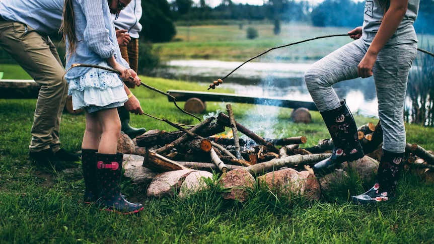 Family toasts marshmallows around a campfire for a story about surviving school holidays as a family.