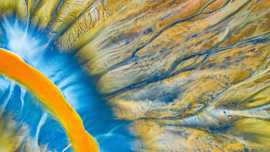 An aerial image of a river with sections of bright blue, orange and yellow.