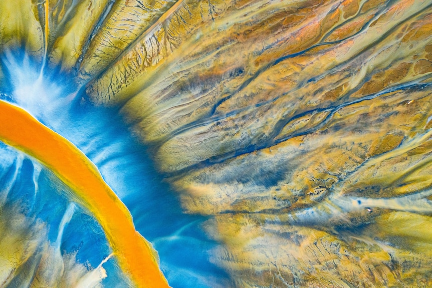 An aerial image of a river with sections of bright blue, orange and yellow.