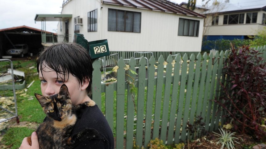 Nathan Long walks with his cat, Marbles, outside his damaged home in Tully.