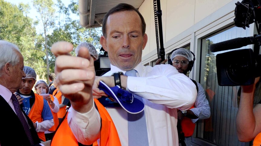 Tony Abbott pulls on a safety vest