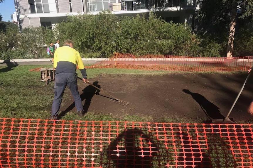 Council workers smooth dirt where the concrete slab was