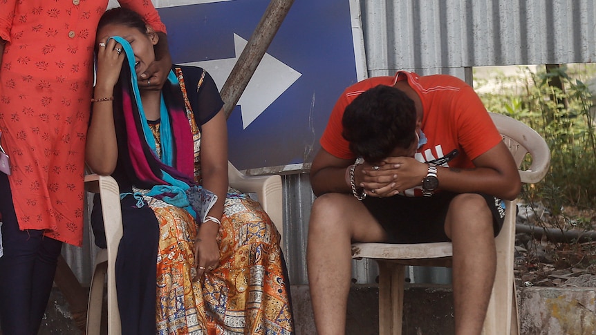 A woman and a man sit on plastic chairs and cry.