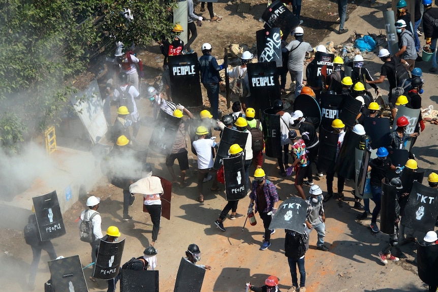 Tear gas smoke rises where protesters and riot police stand