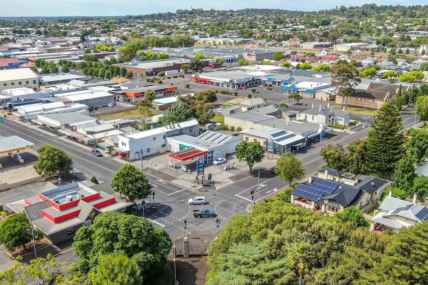 An aerial photo of a lush town with relatively empty streets and carparks.