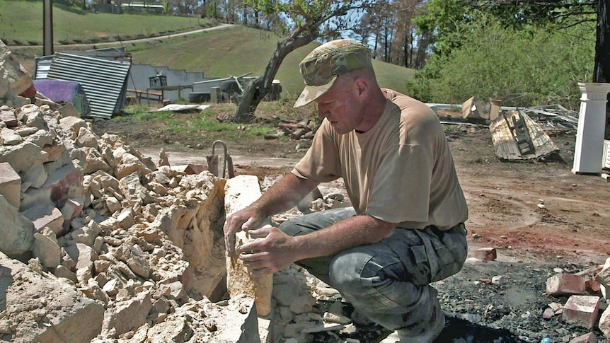 Adam Weinert sorts through the rubble of his home.