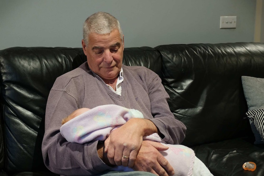 Stephen Longmuir cradles a newborn baby in his arms while seated