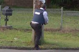 A police officer stands behind a power pole during an hour-long shooting incident at Wyong, Central Coast in March 2020.