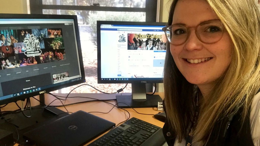 Young woman in front of two computer screens smiling