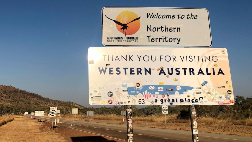 A sign says "Welcome to the Northern Territory" and "Thank you for visiting Western Australia".
