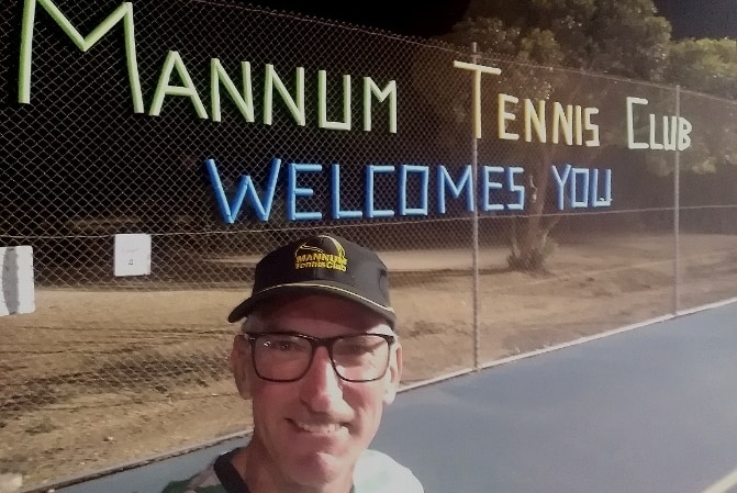 Man in front of a sign that says Mannum Tennis Club