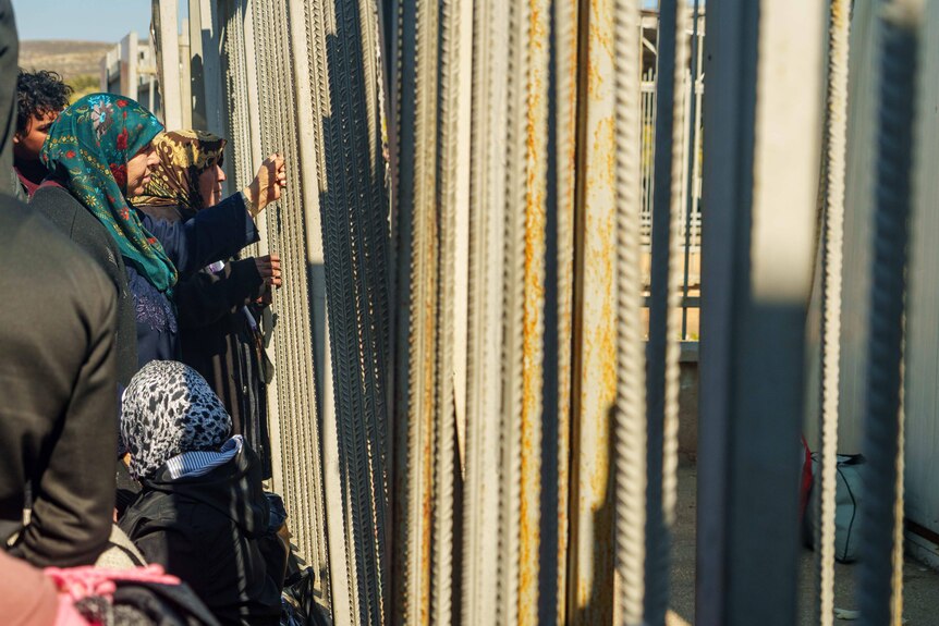 A group of people stand at a make-shift fence.