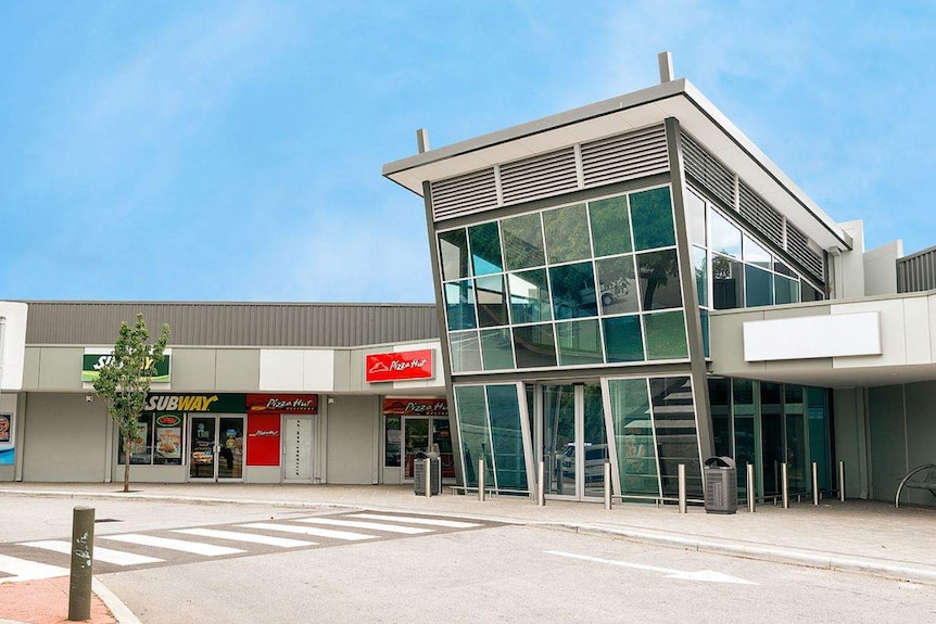 A modest glass-fronted shopping centre with pizza hut and subway restaurants out front.