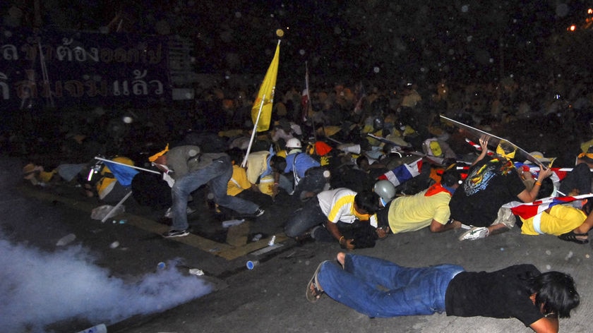 Protesters lie on the ground after riot police used tear gas outside police headquarters in Bangkok.