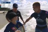 Screenshot from World Surf League tweeted footage of Mick Fanning giving a young fan his surfboard on the shoreline of the beach
