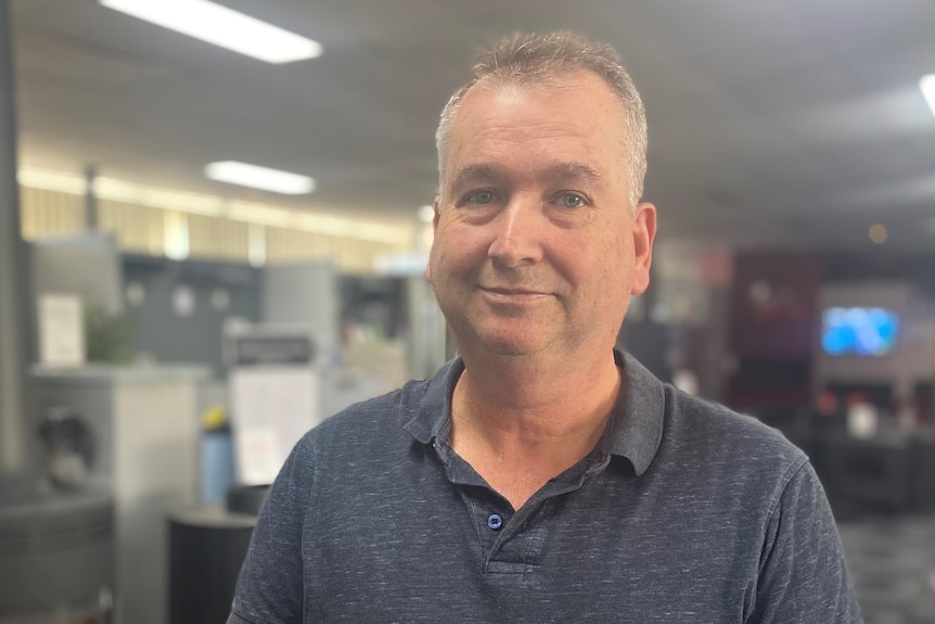 A man with grey hair walks smiles at the camera