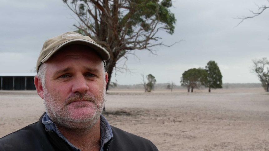 Seaspray farmer Andy McNaughton stands in front of bare, windswept paddocks