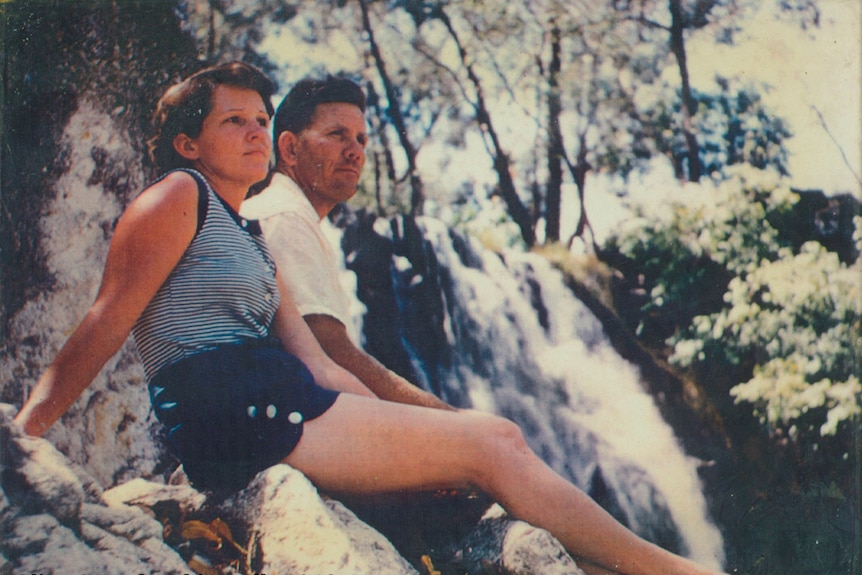 a young woman sits next to her husband in front of a waterfall in 1946