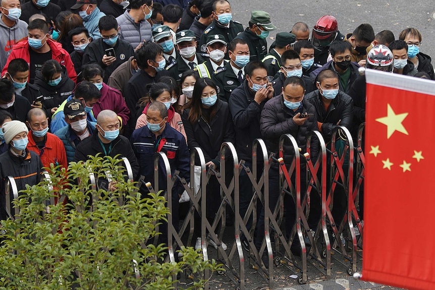 Airport workers in Shanghai stand in a crowded line to be tested for COVID