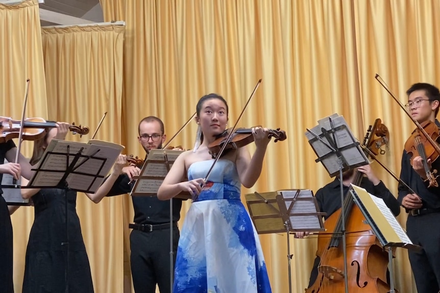 A young violinist plays with a string ensemble.