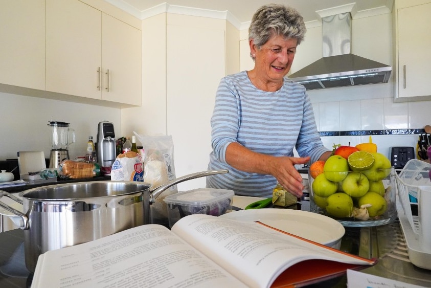 Wendy Hollick reaches for an apple as she prepares to bake a dish in her kitchen.